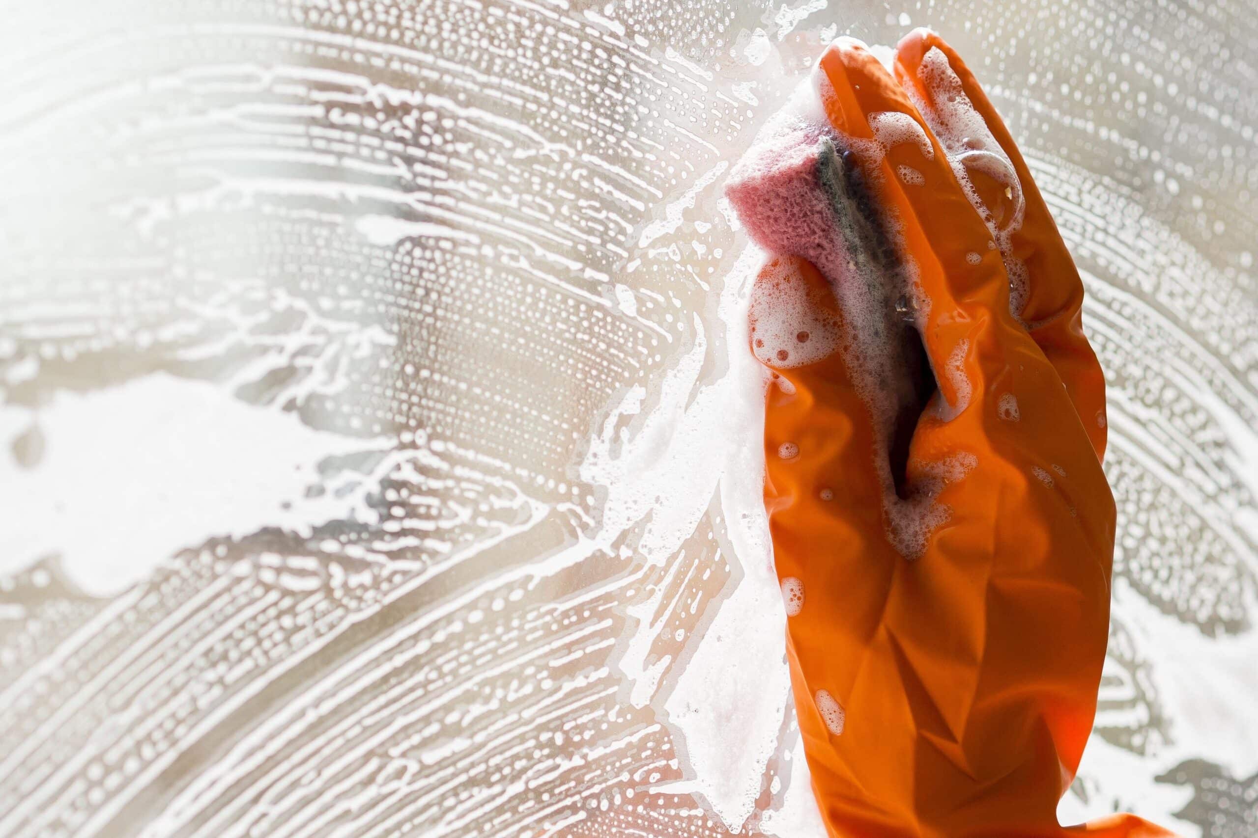 Cleaning office window with gloves and sponge