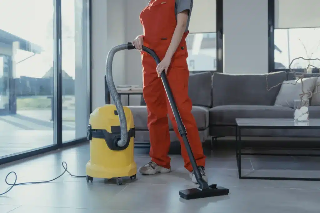 Woman in orange jumpsut cleaning floors with professional cleaning equipment