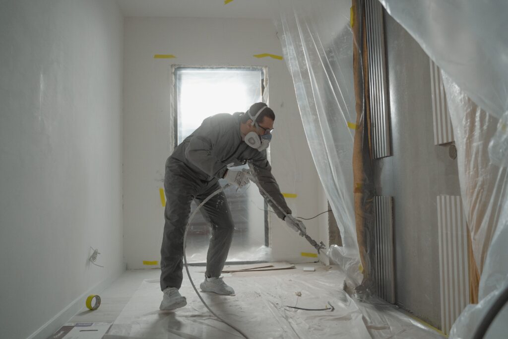 Man power cleaning construction dust on a construction site while wearing a mask
